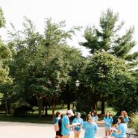 A small group of campers circle up and share their writing surrounded by trees on Grand Valley's campus.